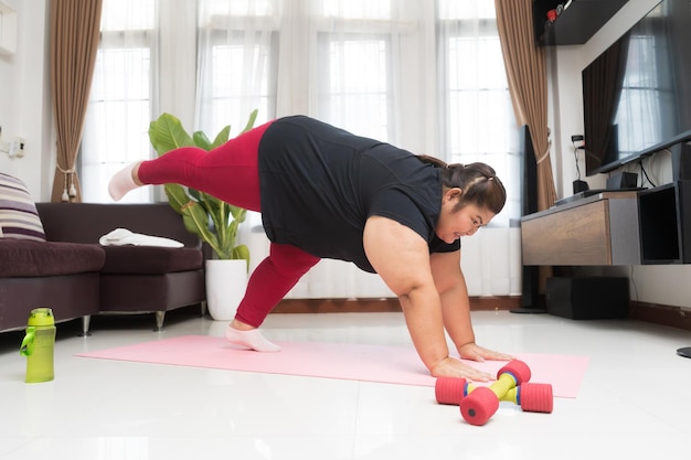 Allenamento grasso della donna asiatica a casa sport che esercita la perdita di peso e il concetto di idea di ricreazione