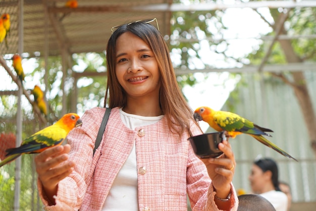 Asian woman feeding parrots in the garden