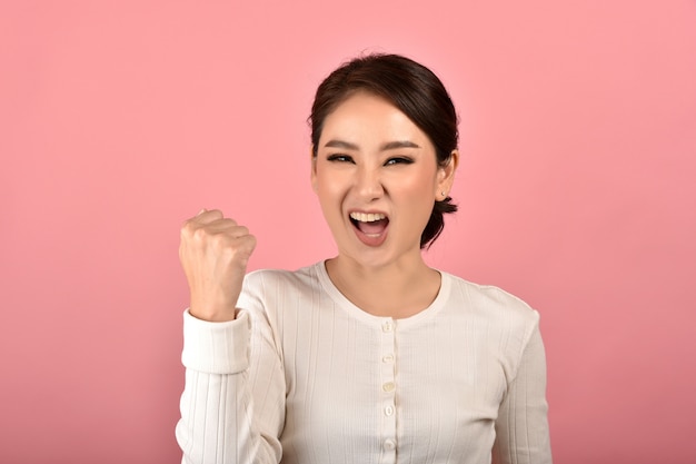 Asian woman feeling happy and excited on accomplish success on pink background, Portrait of smiling winner girl celebrating use for advertising.