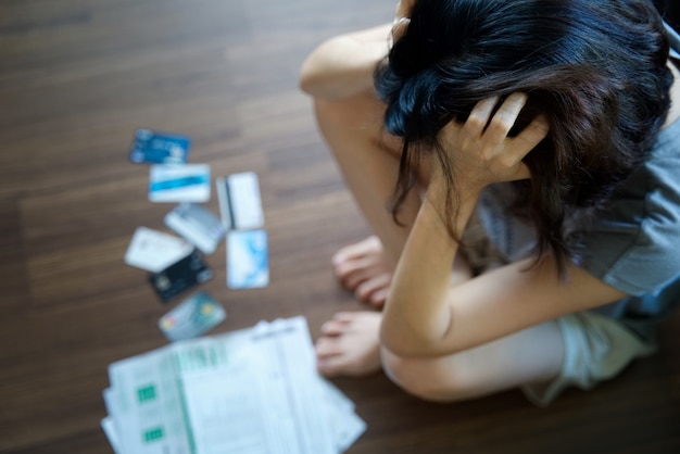 Asian woman feeling headache and thinking how to find money to pay all bills.