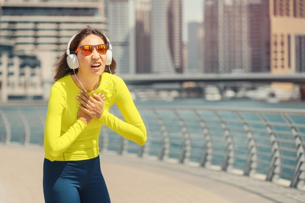 Asian woman felt a strong pain in the chest area while jogging and stopped to rest health problems in the field of cardio system and breathing