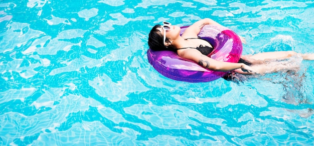 An Asian woman floating in the swimming pool with inflatable tube