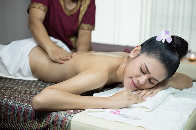 Asian woman getting thai herbal compress massage in spa