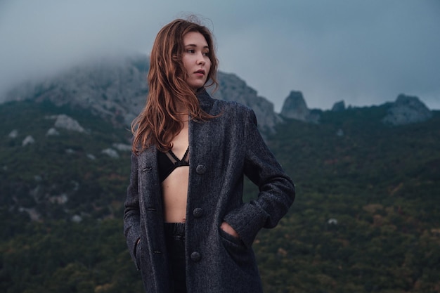 Asian woman in a gray coat enjoying the view in the mountains