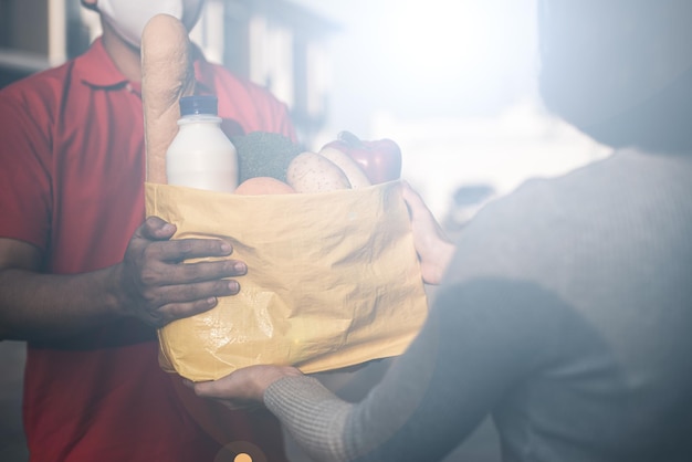 Asian woman hand accepting bag of food fruit vegetable delivery from professional deliveryman