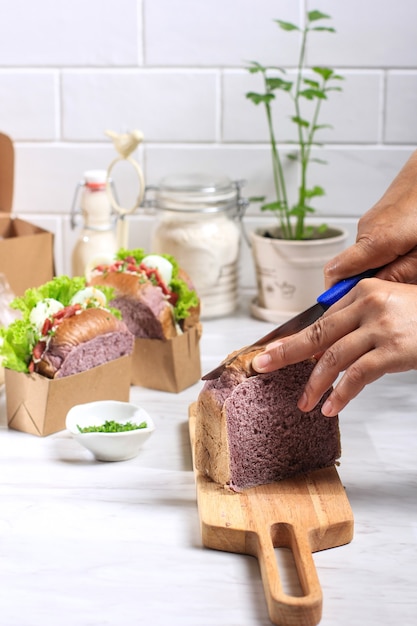 Asian woman hand sliced purple bread made from japanese purple\
yam, preparation making korean healthy egg drop sandwich