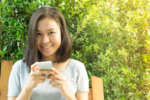 Asian woman hand using mobile phone in garden with copy space