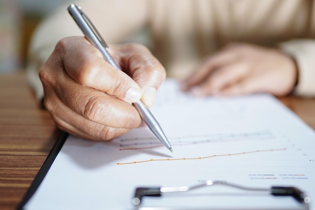 Asian woman hand using pen writing on paper while sitting at the table