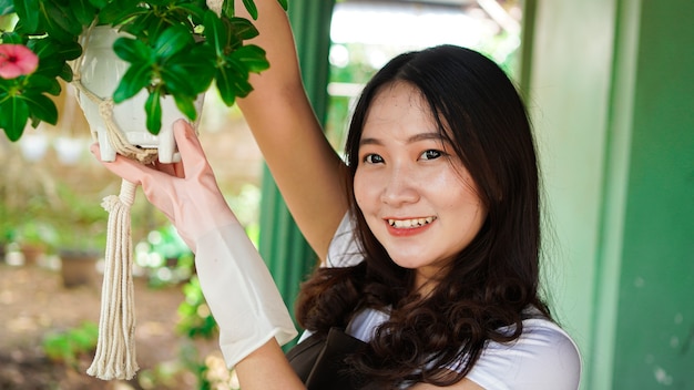 家で植物をぶら下げアジアの女性は美しい装飾を作ります