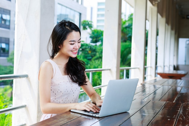 Asian woman happily using a notebook