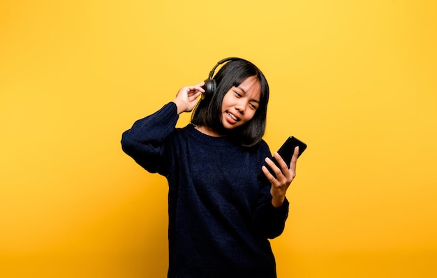 Asian woman happily using the phone and listening to music Relaxing with music On a comfortable day