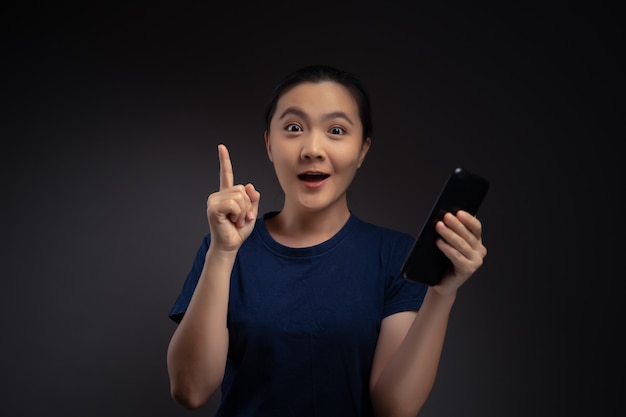 Asian woman happy surprised holding smartphone isolated on background.