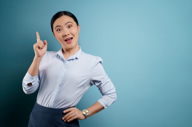 Asian woman happy surprised posing on blue.