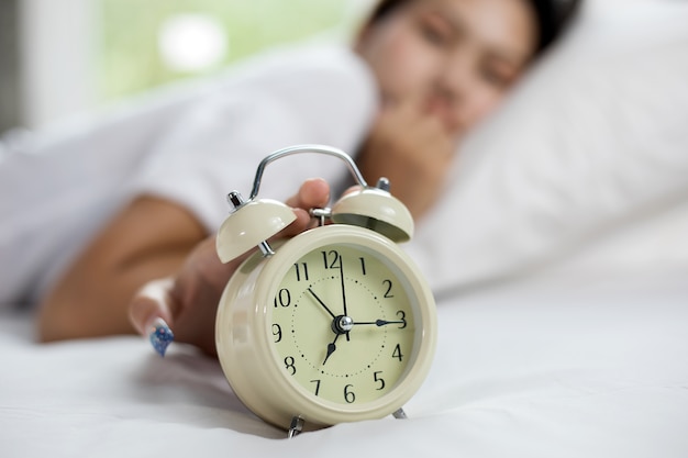 asian woman happy waking up and turning off the alarm clock having a good day