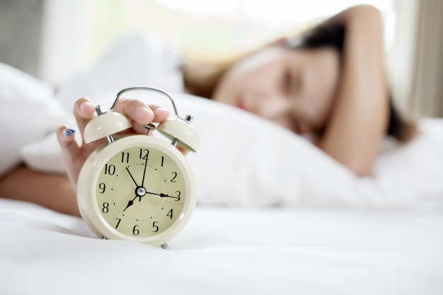 Photo asian woman happy waking up and turning off the alarm clock having a good day