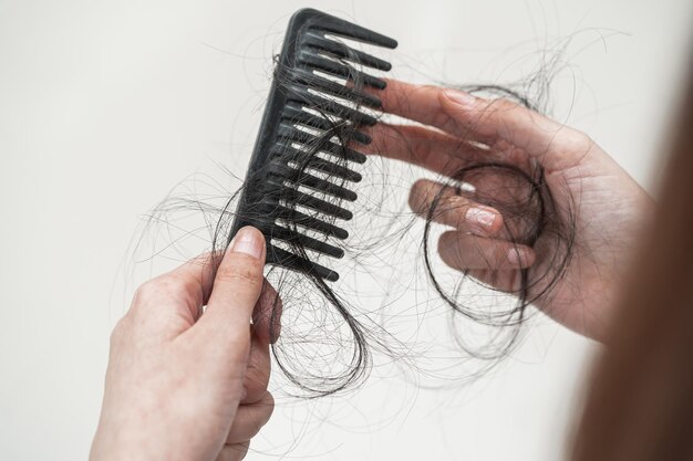 Foto la donna asiatica ha problemi con la perdita dei capelli lunghi attaccata al pettine