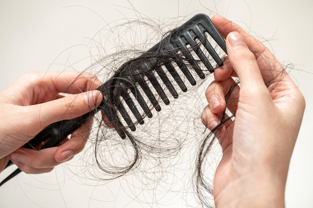 Asian woman have problem with long hair loss attach to comb brush