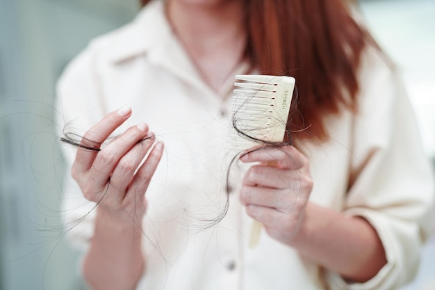 Asian woman have problem with long hair loss attach to comb brush