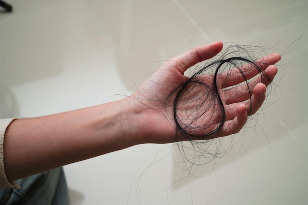 Asian woman have problem with long hair loss attach in her hand