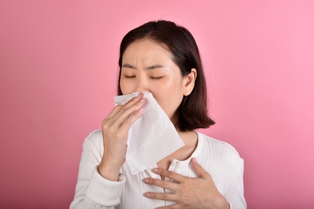 Азиатская женщина страдает аллергией на горло и кашлем, чиханием и кашлем в общественных местах без защиты распространяемой капли коронавирусной болезни (covid-19)