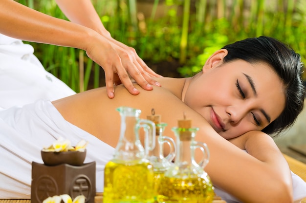 Asian woman having a massage in tropical setting