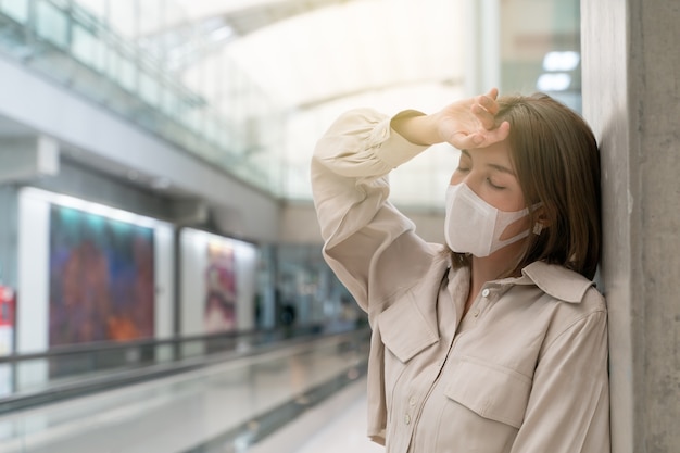 사진 공항 터미널에서 아시아 여성 두통 착용 마스크 새로운 정상 코로나 질환 예방