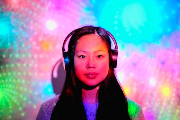 Asian woman in headphones under glowing neon colors