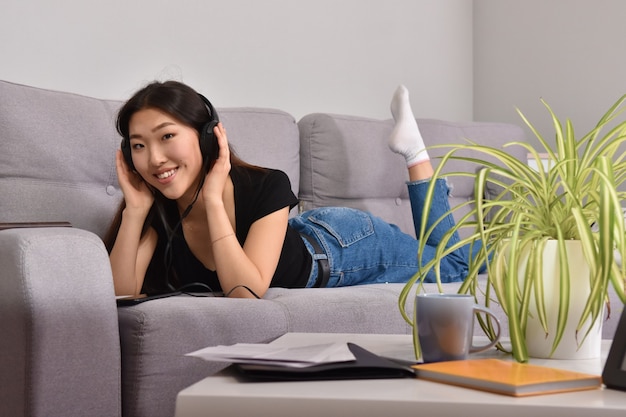 Asian woman in headphones using smartphone