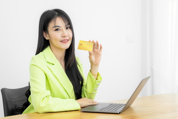 Asian Woman holding bank business credit card with computer laptop Woman hand holding bank credit card Paying using credit card Asian shopaholic shopping online lifestyle