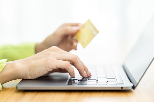 Asian Woman holding bank business credit card with computer laptop Woman hand holding bank credit card Paying using credit card Asian shopaholic shopping online lifestyle