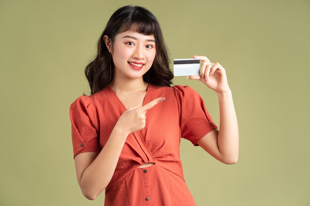 Asian woman holding a bank card and pointing at the bank card