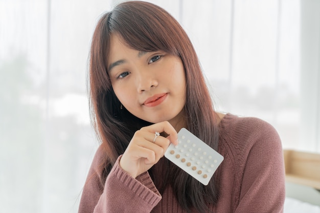 Asian woman holding Birth control pill