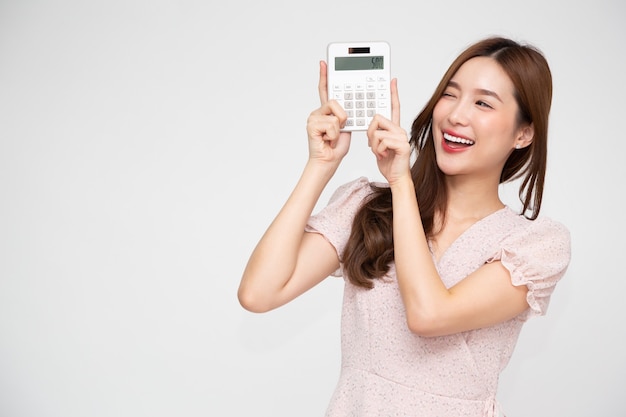 Asian woman holding calculator isolated on white wall.