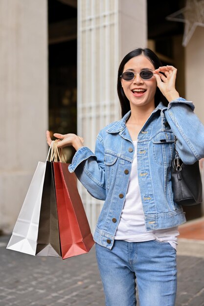 Asian woman holding carrying shopping bags while enjoys\
shopping at city mall center