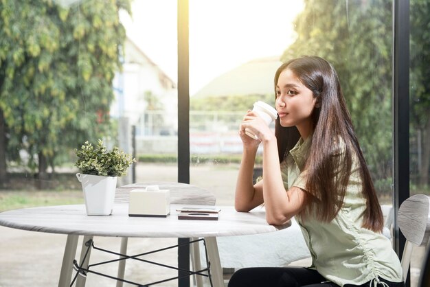 コーヒーショップでコーヒーを保持しているアジアの女性