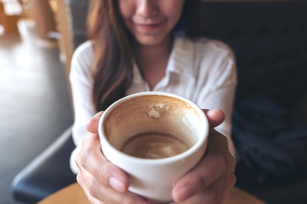 an Asian woman holding a coffee cup and drinking 