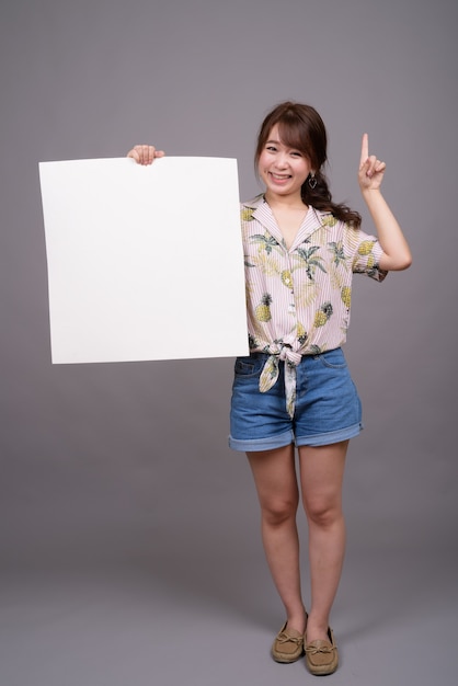 Asian woman holding empty white board with copyspace