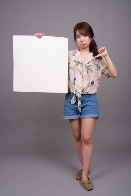 Asian woman holding empty white board with copyspace