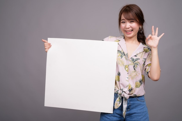 Asian woman holding empty white board with copyspace