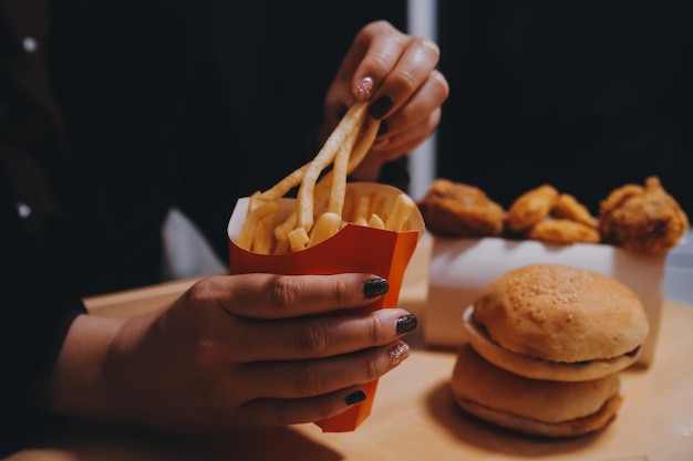 フライドポテトを持ったアジア人女性がレストランで幸せに食べています