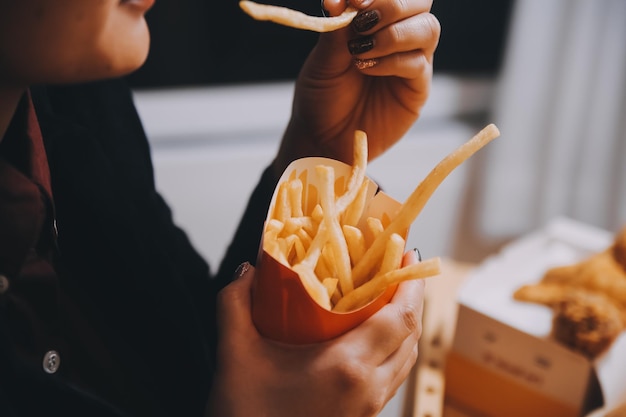 フライドポテトを持ったアジア人女性がレストランで幸せに食べています