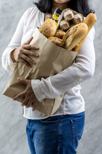 食料品の紙の袋を保持しているアジアの女性