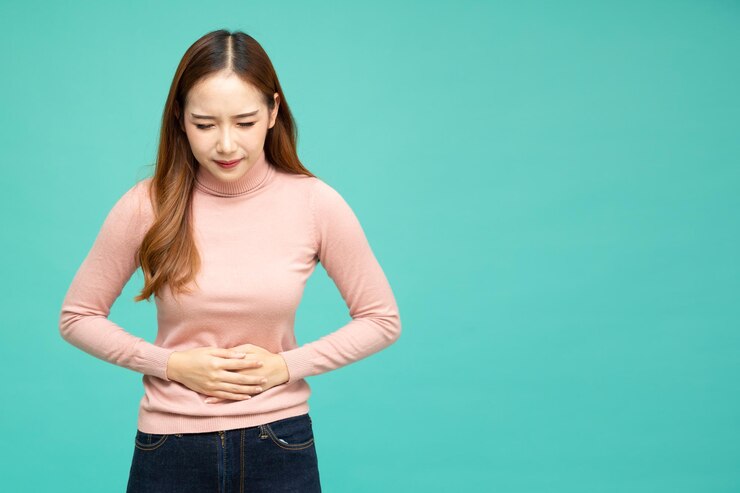 Photo 월경 중 통증과 복통, 녹색 배경에 고립 된 그녀의 위장을 잡고 있는 아시아 여성