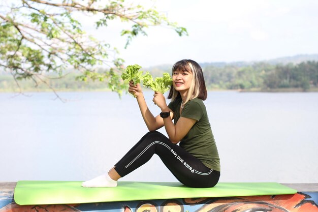 Photo asian woman holding lettuce in the morning