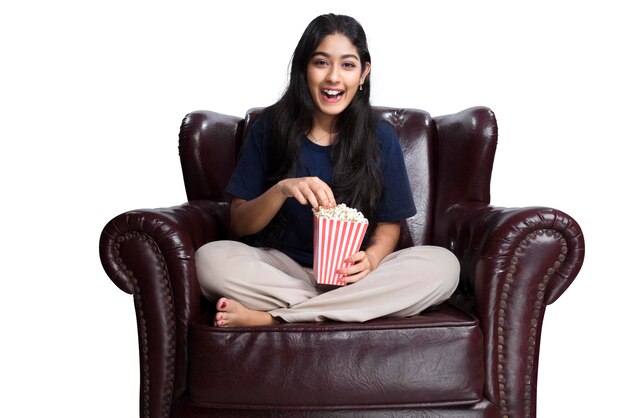 Asian woman holding a popcorn sitting on the couch