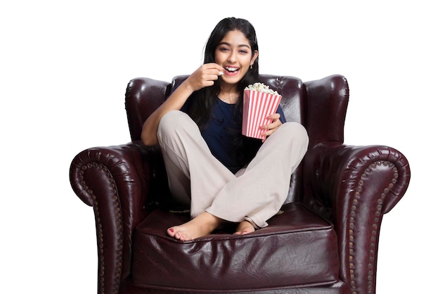 Asian woman holding a popcorn sitting on the couch