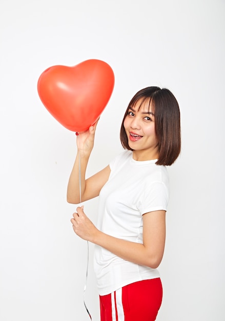 Asian woman holding a red heart balloon 