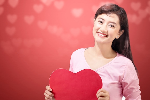 컬러 벽과 붉은 마음을 잡고 아시아 여자. 발렌타인 데이