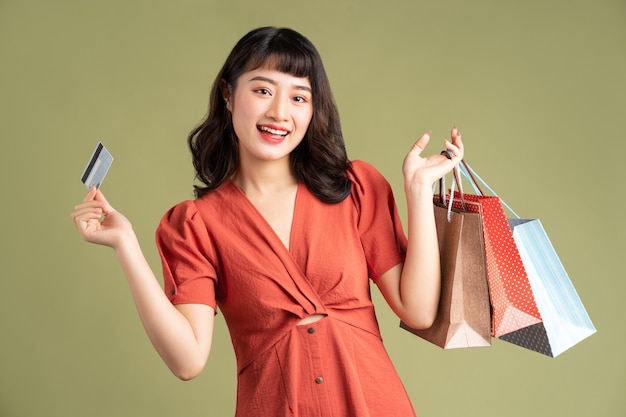 Asian woman holding shopping bag and holding up a bank card