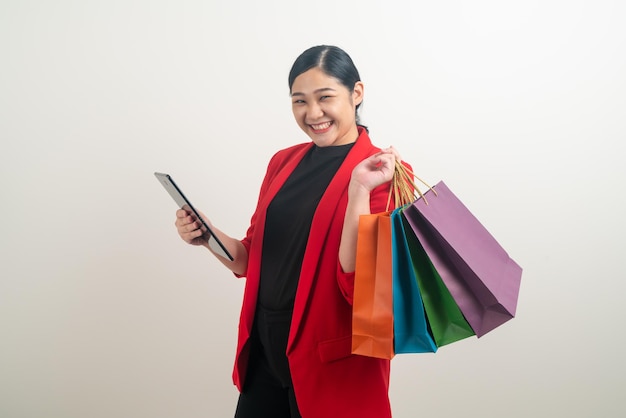 Asian woman holding shopping bag and tablet on hand with white background